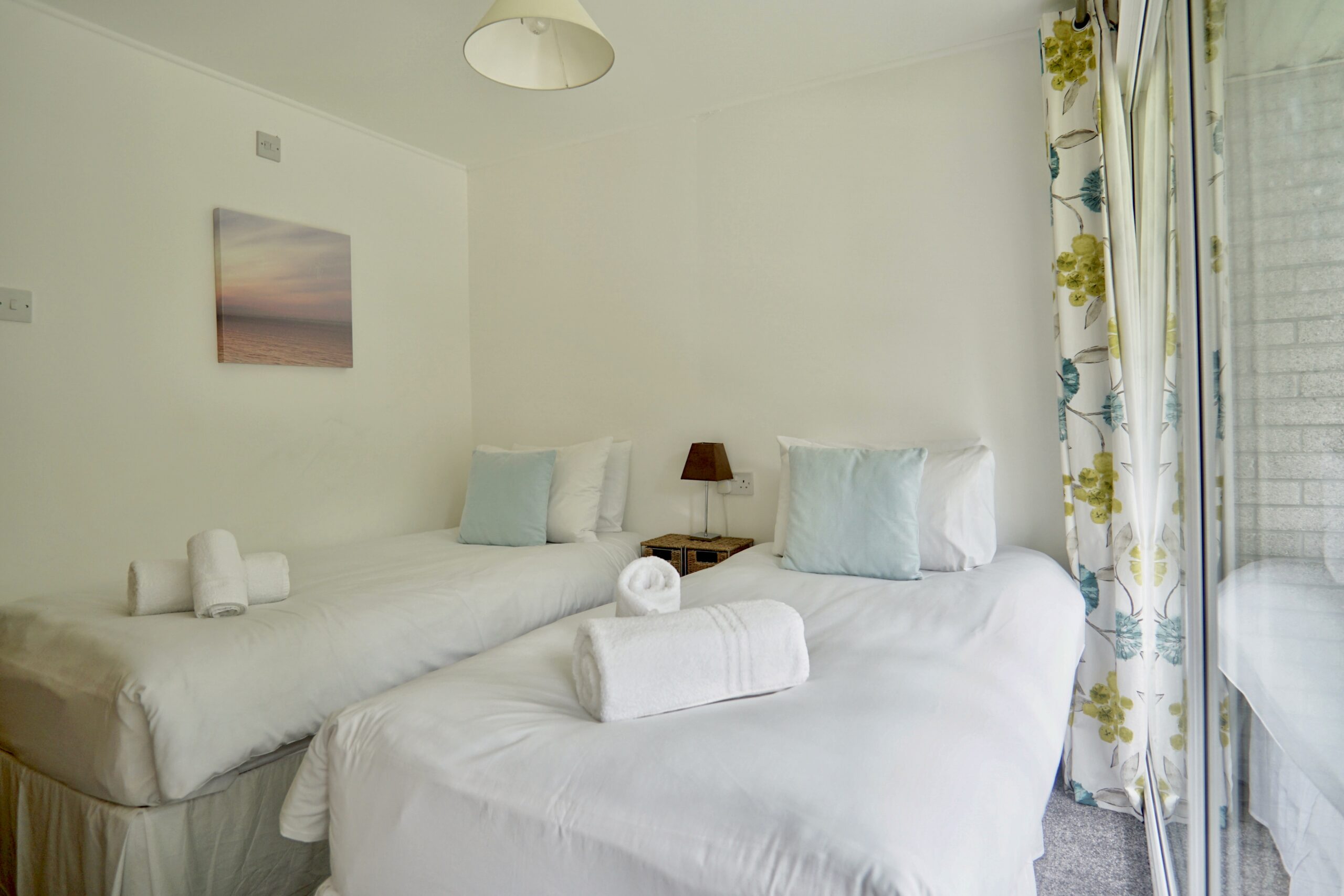 Recently, I photographed a lovely two-bedroom holiday home at Atlantic Reach Resort, a popular holiday park located just outside Newquay. Designed perfectly for couples or young families, the property offered a relaxed and practical base for exploring Cornwall, while still being close enough to enjoy the beaches and town within around fifteen minutes by car.

A Bright and Practical Holiday Home

The property itself was set up ideally for a family of four, with one double bedroom alongside a second bedroom containing two single beds. Downstairs featured an open-plan lounge and kitchenette area, creating a sociable space where families could relax together after a day exploring the coast.

One of the strongest features of the property was the amount of natural light coming into the living space. Large windows at both the front and rear helped brighten the room throughout the day, while also giving views across different parts of the site.

Views Across the Pool and Play Area

To the rear, the property overlooked the children’s play park and site swimming pool, which immediately added to its appeal as a family-friendly holiday let. From a photography perspective, these views helped give context to the location and showed potential guests exactly what was nearby.

At the front, the property overlooked the parking area, making access easy and convenient for families arriving with luggage, beach equipment or young children.

A Relaxed Base Near the Cornish Coast

Atlantic Reach Resort is made up of multiple holiday homes within a well-maintained setting, giving it a relaxed and welcoming atmosphere. Its location works particularly well for visitors wanting easy access to Newquay’s beaches, restaurants and attractions without being directly in the centre of town.

For holiday let owners, professional photography plays a huge role in helping properties stand out online, especially in busy coastal areas like Cornwall where guests are comparing large numbers of listings.

Showcasing Space and Lifestyle

When photographing holiday accommodation, the aim is always to show more than just the rooms themselves. Good imagery should help guests picture their stay before they even arrive, whether that is relaxing in the lounge after a beach day or watching children play from the rear windows.

This Atlantic Reach property combined practicality, location and family-friendly surroundings, making it an ideal holiday base and a great property to photograph.